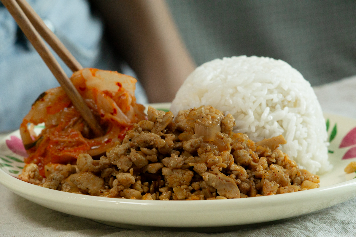 assembling tofu bulgogi on a plate with rice and kimchi