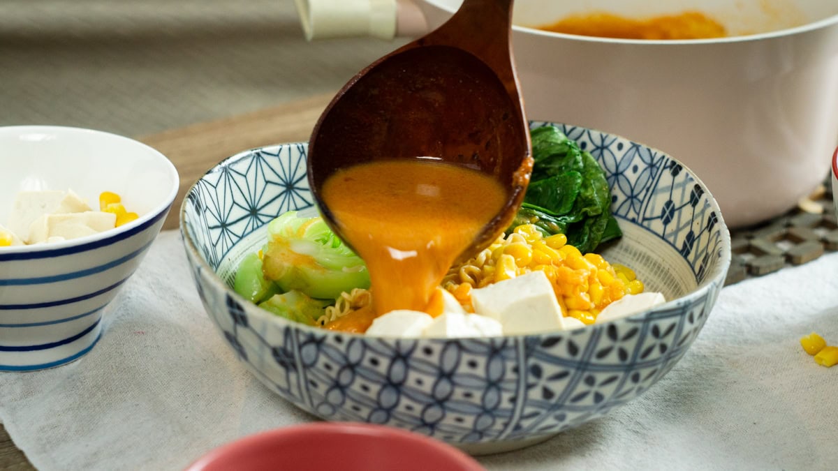 pouring broth over to make vegan miso ramen