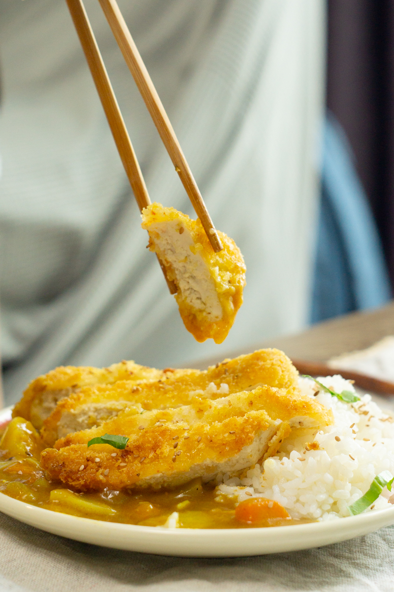 holding a piece of tofu katsu with chopsticks