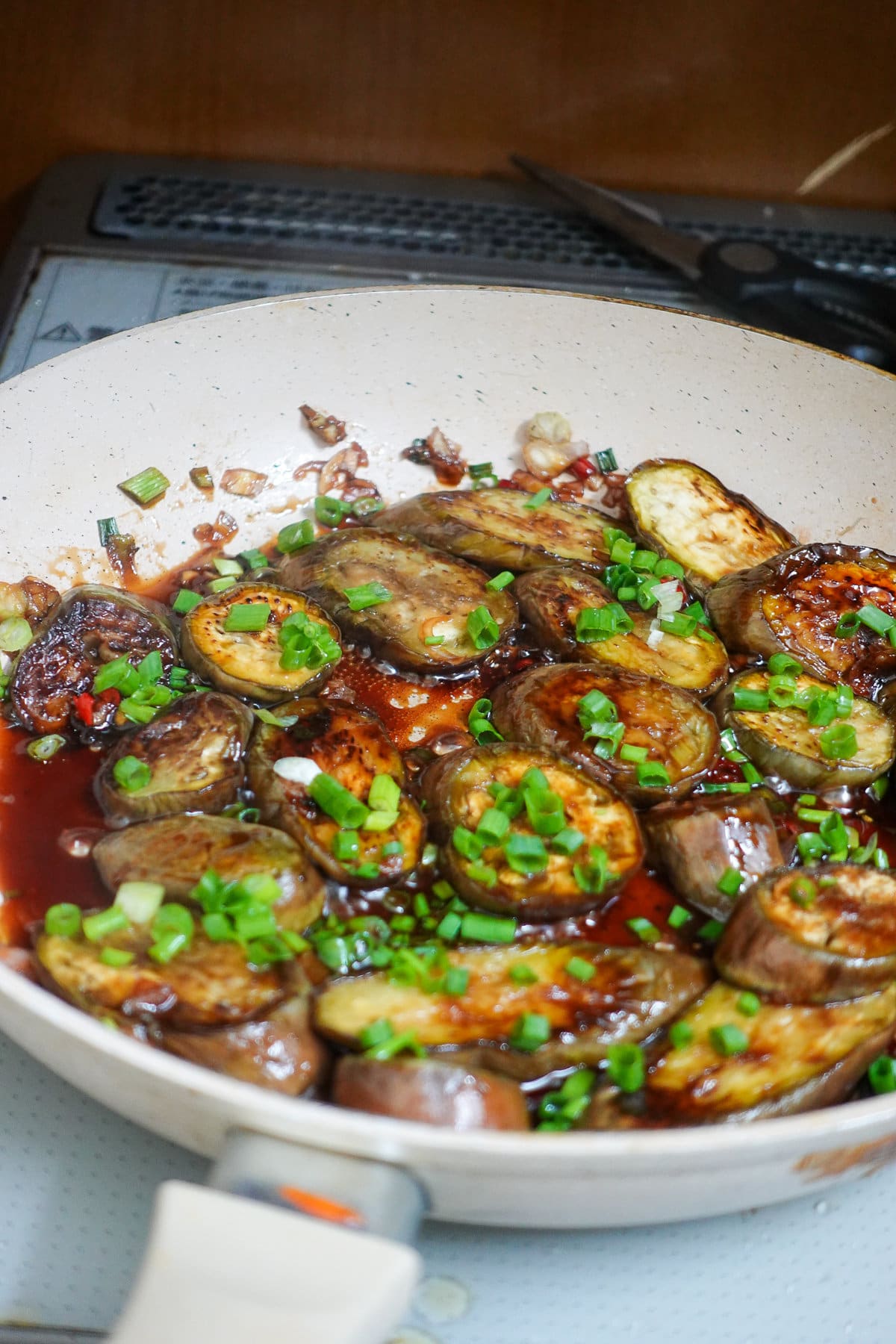 a skillet of eggplant with scallions on top