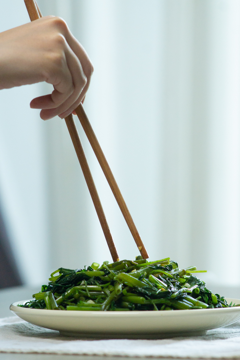 eating stir fried morning glory with chopsticks