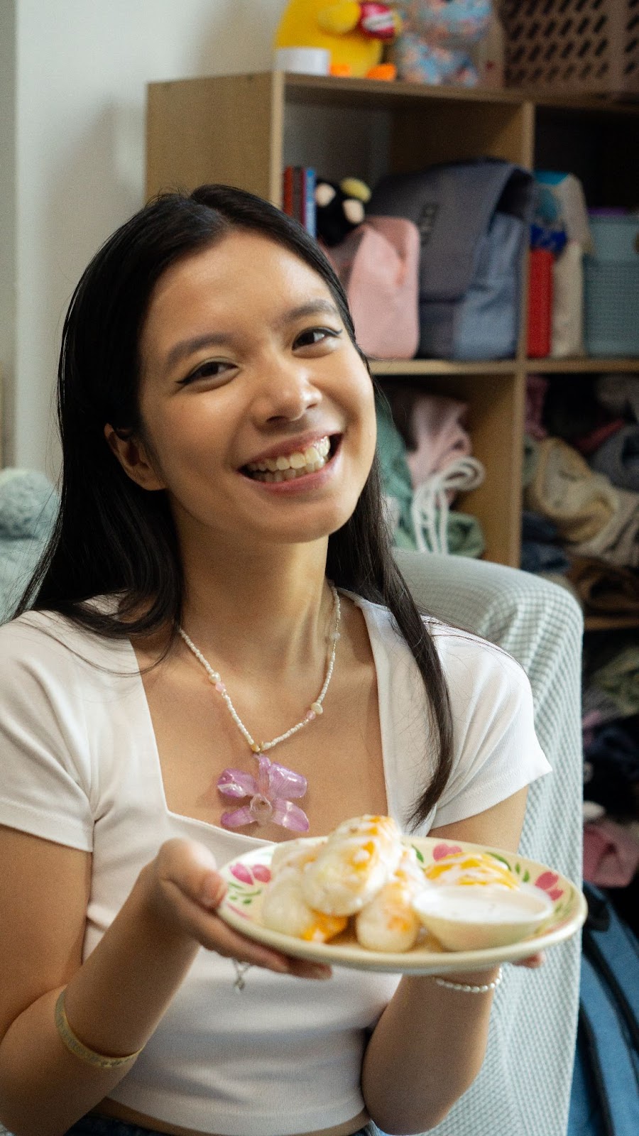 A person smiling while holding a plate of mango sticky rice rolls 