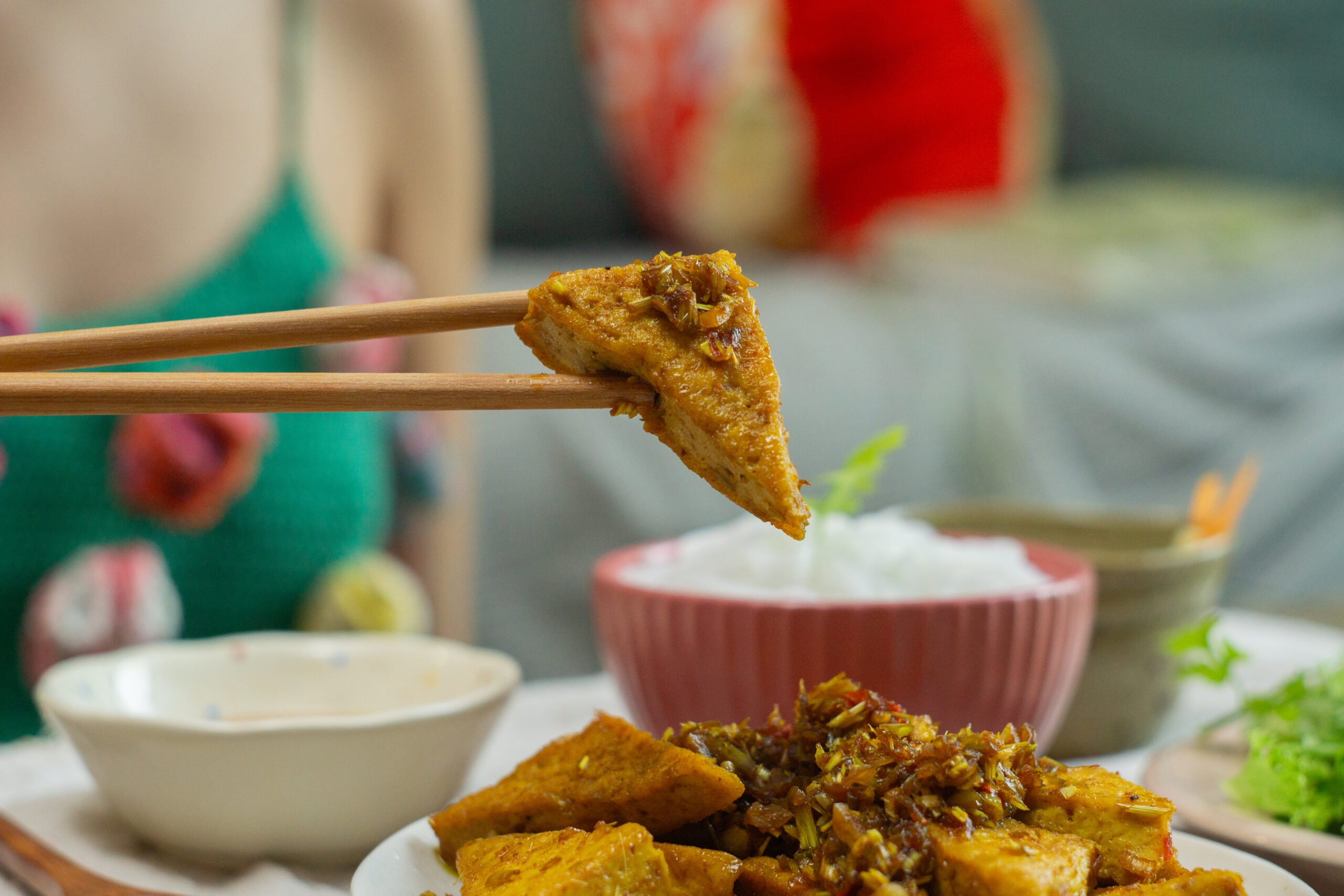 holding a piece of tofu with chopsticks