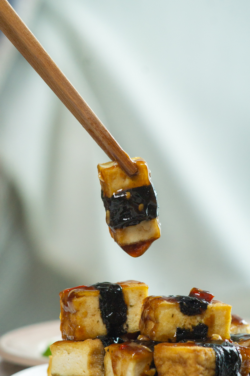 a piece of nori wrapped tofu coated in sauce