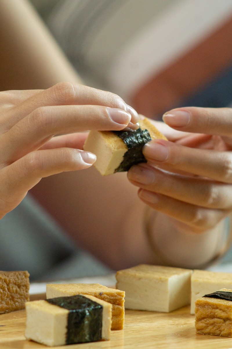 wrapping the nori strip around a piece of tofu