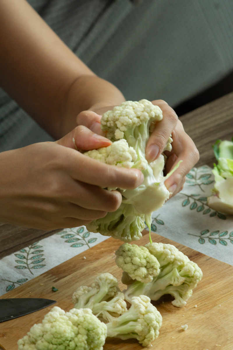breaking the cauliflower into smaller florets