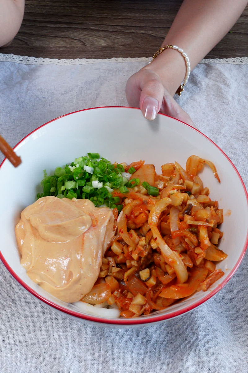 assembling vegan kimchi udon in a bowl